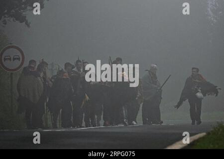 I pellegrini cattolici romani chiamati Romeiros attraversano una strada rurale nella fitta nebbia e soffia pioggia durante il loro trekking di 8 giorni intorno all'isola delle Azzorre di Sao Miguel, il 26 marzo 2023 a Povoação, in Portogallo. I pellegrini visitano 100 santuari e chiese durante l'evento che risale al 1522, quando un terremoto distrusse i primi insediamenti. Foto Stock