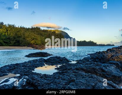 Le rocce e le piscine di Lave presso la spiaggia di Lumaha'i sull'isola hawaiana di Kauai con le montagne di Na Pali alle spalle. Preso all'alba Foto Stock