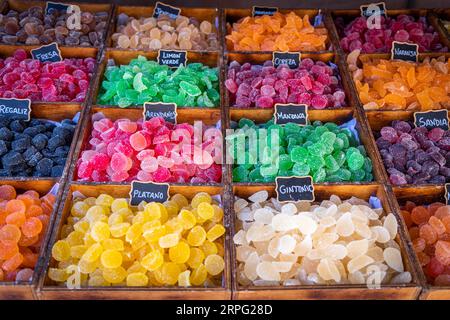 caramelle dolci di diversi colori e consistenze, esposte in primo piano, con zucchero sopra e su un contenitore rustico di legno Foto Stock