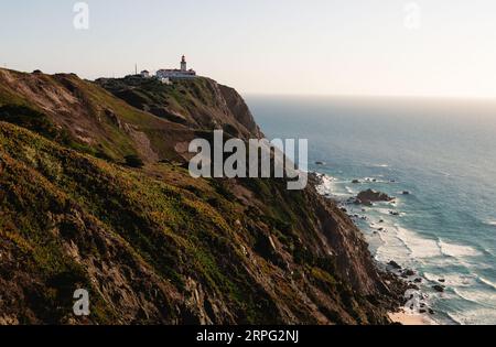 Vista di Capo Roca con faro rosso - Sintra Portogallo. Viaggia e punto di riferimento turistico con le splendide scogliere costiere dell'oceano atlantico al tramonto. Foto Stock
