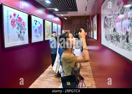 191006 -- FUZHOU, 6 ottobre 2019 -- Un visitatore scatta foto di una mostra durante una mostra con dipinti di peonia, durante la festa nazionale a Fuzhou, capitale della provincia del Fujian della Cina sud-orientale, 6 ottobre 2019. CINA-FESTA NAZIONALE-TURISMO CN JIANGXKEHONG PUBLICATIONXNOTXINXCHN Foto Stock