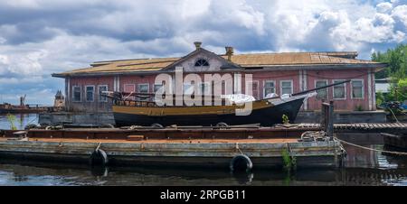 vecchi moli di legno, una nave a vela è ormeggiata accanto a una casa galleggiante del molo Foto Stock