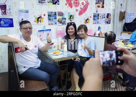 191012 -- HONG KONG, 12 ottobre 2019 -- Kate Lee 3rd L posa per una foto con i clienti al suo ristorante di tè a Kowloon, nel sud della Cina, Hong Kong, 10 ottobre 2019. Annidato nel labirinto mercato di pesce del tranquillo villaggio di pescatori lei Yue Mun a Hong Kong, un piccolo e accogliente ristorante per il tè è diventato inaspettatamente un faro di coraggio per la gente comune di Hong Kong che cerca la pace nel recente caos. Dopo aver postato foto a sostegno della polizia di Hong Kong contro alcuni manifestanti radicali alla fine di giugno, Kate Lee, la proprietaria del ristorante del tè, ha scoperto che la sua coscienza ha fatto un pesante tributo alla sua famiglia Foto Stock