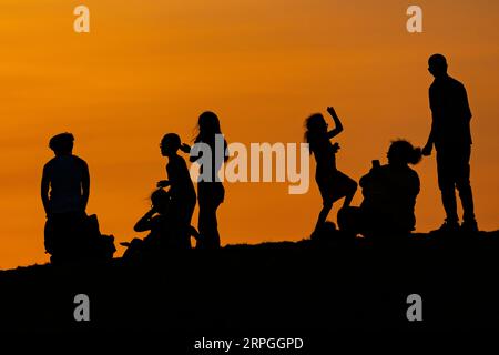 Londra, Regno Unito. 4 settembre 2023. Meteo del Regno Unito – la gente si gode il tramonto in cima ai tumuli artificiali di Northala Fields a Northolt, nella parte ovest di Londra. Il Met Office prevede temperature elevate che toccheranno i 30 °C per la settimana, poiché gli effetti di un cosiddetto pennacchio iberico saranno avvertiti su gran parte del paese. Crediti: Stephen Chung / Alamy Live News Foto Stock