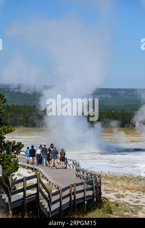 La folla osserva i geyser eruttare nel bacino dei geyser nel parco nazionale di Yellowstone Foto Stock