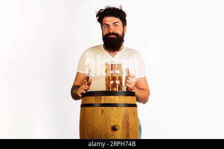 Festa dell'Oktoberfest. Alcol. Tradizioni tedesche. Uomo barbuto con tazza di birra lager su botte di legno. Birreria. Botte di legno e vetro Foto Stock