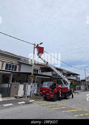 La scena all'aperto in cui i lavoratori cambiano l'asta della lampadina del lampione stradale con il carrello scaletta posteriore Foto Stock