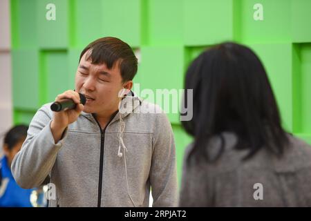 191203 -- HOHHOT, 3 dicembre 2019 -- Surina ascolta un partecipante ipovedente mentre recita una poesia durante il corso di formazione in una biblioteca per persone con disabilità a Hohhot, capitale della regione autonoma della Mongolia interna della Cina settentrionale, 3 dicembre 2019. Surina, anchorwoman della stazione televisiva Inner Mongolia, ha iniziato il suo programma Light of the Heart nel 2017 con l'obiettivo di aiutare le persone ipovedenti a conoscere meglio il mondo mostrando e descrivendo i film per loro. Ora ha fatto un ulteriore passo avanti fornendo un corso di formazione per i non vedenti da apprezzare e r Foto Stock