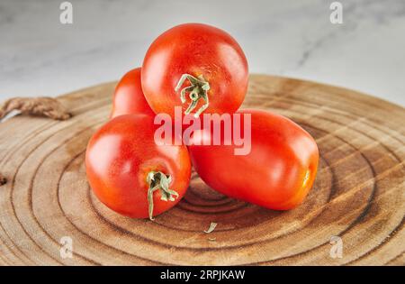 Prugna di pomodoro impilata in collina su uno sfondo di legno su marmo bianco Foto Stock