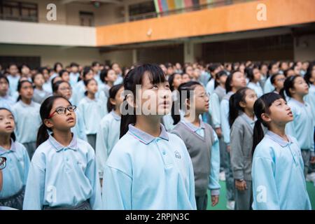 191215 -- MACAO, 15 dicembre 2019 Xinhua -- Yu in sin C e i suoi compagni di scuola partecipano a una cerimonia di innalzamento della bandiera alla Premier School affiliata alla Hou Kong Middle School a Macao, Cina meridionale, 25 novembre 2019. Yu di 10 anni, nato a Macao, è uno studente di quinta elementare della Premier School affiliata alla Hou Kong Middle School. Anche suo fratello studia alla scuola. Agli occhi di sua madre, Yu in sin è una ragazza ottimista, solare e vivace con molti talenti. Ha vinto molti premi nelle competizioni di narrazione, recitazione, arte e danza degli studenti delle scuole primarie di Macao. Anche se nato dopo Macao S retu Foto Stock