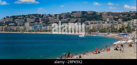 Nizza, Francia - 28 maggio 2023: Gente sulle famose spiagge lungo la Promenade des Anglais con la costa del Mar Mediterraneo sullo sfondo, Costa Azzurra Foto Stock