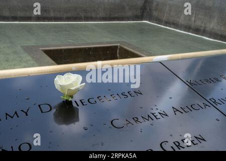 New York, USA - 21 luglio 2023: Una rosa bianca su uno dei nomi delle vittime dell'11 settembre, scolpita intorno alle due piscine nel memoriale dell'11 settembre a ne Foto Stock