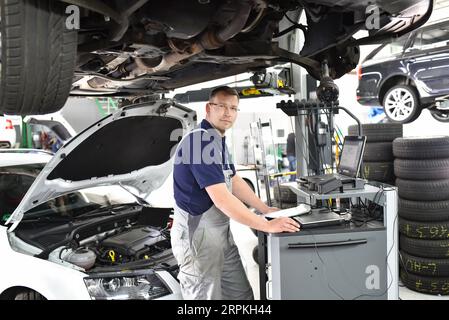 Autofficine mantiene un veicolo con la guida di un computer diagnostico - tecnologia moderna per la riparazione auto shop Foto Stock