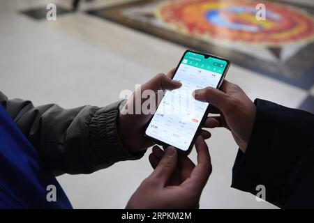 200113 -- LANZHOU, 13 gennaio 2020 -- Un volontario aiuta un passeggero a controllare le informazioni del treno alla stazione ferroviaria di Lanzhou, capitale della provincia del Gansu della Cina nord-occidentale, 13 gennaio 2020. Durante la corsa al Festival di Primavera, la stazione ferroviaria di Lanzhou e la stazione ferroviaria di Lanzhou West realizzano un servizio volontario speciale chiamato Steward of the Journey . Per i passeggeri che hanno preso degli appuntamenti, che hanno fretta di salire sui treni o che non hanno familiarità con il sistema di biglietteria mobile, i volontari sono a disposizione per fornire il servizio e aiutarli a ridurre i tempi di salita sui treni, portando i passeggeri c Foto Stock