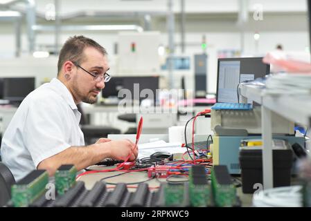 In ingegneria microelettronica: i lavoratori nella produzione e assemblaggio di electronic high tech componenti in un moderno stabilimento Foto Stock