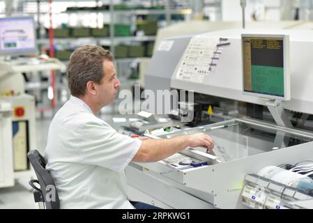 In ingegneria microelettronica: i lavoratori nella produzione e assemblaggio di electronic high tech componenti in un moderno stabilimento Foto Stock