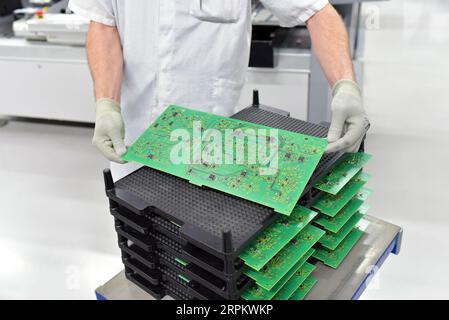 produzione e assemblaggio di schede a circuito stampato in una fabbrica industriale - i lavoratori controllano la qualità Foto Stock