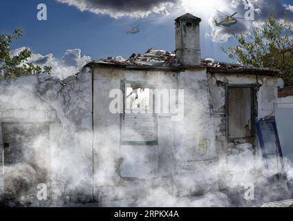 Guerra, danni e attacchi con casa e fumo da pericolo, caos fuoco e devastazione. Elicottero, crisi e abbandonato con struttura di costruzione rotta Foto Stock