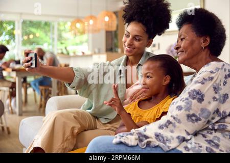 Famiglia femminile di più generazioni in posa per selfie su un telefono cellulare seduto sul divano a casa Foto Stock