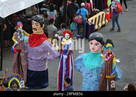 Festa di benvenuto a tema festa filippina per la nave da crociera al molo di Manila: Musicisti con strumenti di bambù, ballerini filippini, Higantes, bandiere Foto Stock