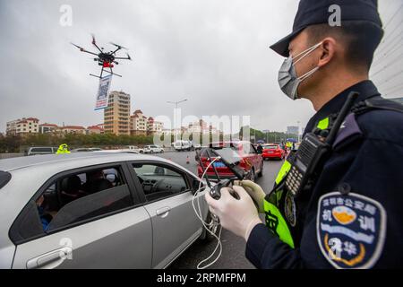 200211 -- SHENZHEN, 11 febbraio 2020 Xinhua -- Un agente di polizia gestisce un drone che porta un cartello con il codice QR vicino a una stazione a pedaggio autostradale a Shenzhen, nella provincia del Guangdong della Cina meridionale, 11 febbraio 2020. Come misura per contribuire a prevenire e controllare il nuovo coronavirus, un sistema di registrazione online per i veicoli che tornano a Shenzhen è stato messo in uso dall'8 febbraio. Per aumentare l'efficienza, gli agenti di polizia locali hanno utilizzato droni per portare un codice QR alle uscite dell'autostrada per consentire ai conducenti di registrarsi con meno contatti con altre persone. Foto di Lai li/Xinhua CHINA-SHENZHEN-NCP-QR CODE-REGISTER CN PUBLICAT Foto Stock