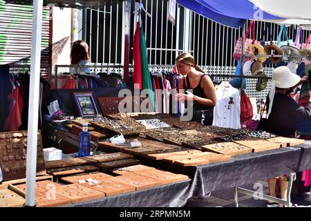 Madrid, Spagna - 20 agosto 2023: Donna che sceglie bigiotteria nel mercato di strada. Questo mercato delle pulci si chiama El Rastro e migliaia di persone lo visitano ogni domenica. Foto Stock