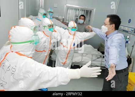 200218 -- WUHAN, 18 febbraio 2020 -- Mr. Wang, 36, un paziente recuperato da coronavirus, abbraccia il personale medico senza contatto corporeo prima di lasciare il Leishenshan Thunder God Mountain Hospital a Wuhan, capitale della provincia di Hubei, 18 febbraio 2020. Leishenshan Hospital, un ospedale improvvisato costruito a Wuhan in mezzo alla nuova malattia da coronavirus COVID-19, martedì ha visto i suoi primi due pazienti curati, tra cui Wang e una paziente donna di 83 anni. Foto di Gao Xiang/Xinhua CHINA-HUBEI-WUHAN-LEISHENSHAN HOSPITAL-CURED PATIENTS CN CaixYangtonglian PUBLICATIONxNOTxINxCHN Foto Stock