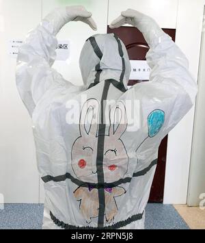 200223 -- WUHAN, 23 febbraio 2020 -- foto non datata mostra uno staff medico che mostra il disegno sulla tuta protettiva nel reparto di isolamento dei bambini infettati da nuova polmonite da coronavirus nell'ospedale dei bambini di Wuhan a Wuhan, nella provincia di Hubei della Cina centrale. Nel reparto di isolamento dei bambini infettati da nuova polmonite da coronavirus nell'ospedale pediatrico di Wuhan, molti bambini avevano paura di vedere il personale medico avvolto in tute protettive. Wang Jia, un'infermiera dell'ospedale che ama disegnare, ha avuto l'idea di disegnare cartoni animati sulle tute protettive e invitare i bambini a colorare il Foto Stock