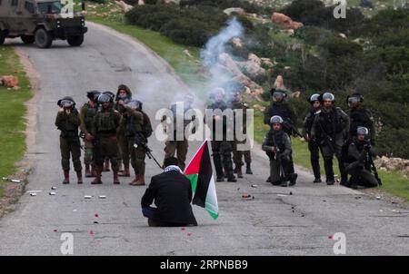 200226 -- PECHINO, 26 febbraio 2020 Xinhua -- Un uomo palestinese siede di fronte ai soldati israeliani durante gli scontri al checkpoint di Tayasir vicino alla città di Tubas in Cisgiordania, il 25 febbraio 2020. Dozzine di manifestanti palestinesi si sono scontrati martedì con soldati israeliani a un blocco stradale dell'esercito israeliano su una strada che conduce alla valle del Giordano in Cisgiordania, hanno detto fonti mediche e di sicurezza. Foto di Nidal Eshtayeh/Xinhua XINHUA FOTO DEL GIORNO PUBLICATIONxNOTxINxCHN Foto Stock