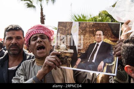 200226 -- CAIRO, 26 febbraio 2020 -- Un sostenitore dell'ex presidente egiziano Hosni Mubarak ha una sua foto al Cairo, Egitto, 26 febbraio 2020. L'Egitto ha tenuto un funerale militare mercoledì per l'ex presidente del paese Hosni Mubarak, morto martedì all'età di 91 anni. EGITTO-CAIRO-HOSNI MUBARAK-FUNERALE WuxHuiwo PUBLICATIONxNOTxINxCHN Foto Stock