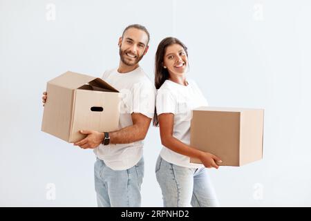 Allegra coppia di Millennial che trasporta scatole di cartone, materiale da imballaggio per il trasferimento Foto Stock