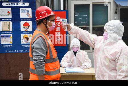 200229 -- CHONGQING, 29 febbraio 2020 -- Un lavoratore ha la temperatura presa in un cantiere del tunnel di Zengjiayan nel distretto di Yuzhong, nella municipalità di Chongqing della Cina sud-occidentale il 29 febbraio 2020. La costruzione di grandi progetti locali è stata ripresa con misure rigorose adottate per prevenire e controllare la nuova epidemia di coronavirus. CHINA-CHONGQING-COSTRUZIONE-RIPRESA CN WangxQuanchao PUBLICATIONxNOTxINxCHN Foto Stock