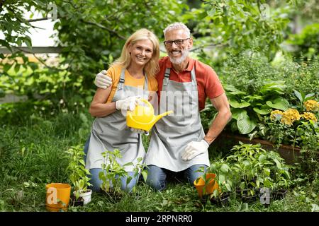 Concetto di giardinaggio. Sposi maturi felici che piantano insieme in giardino Foto Stock