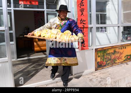 200313 -- TIANZHU, 13 marzo 2020 -- Song Tianzhu trasporta panini fatti in casa nel villaggio di Nannigou della contea autonoma tibetana di Tianzhu, provincia del Gansu della Cina nord-occidentale, 12 marzo 2020. Sfruttando appieno le vaste praterie locali e il sostegno finanziario del governo per le regioni povere, il reddito familiare annuale della famiglia Song Tianzhu ha raggiunto 200.000 yuan circa 28.553 dollari statunitensi attraverso l'allevamento e il turismo. Inoltre, Song prese il comando nella fondazione di una cooperativa per aumentare i redditi degli altri abitanti del villaggio. Con i grandi sforzi compiuti dal governo locale e dal villaggio Foto Stock