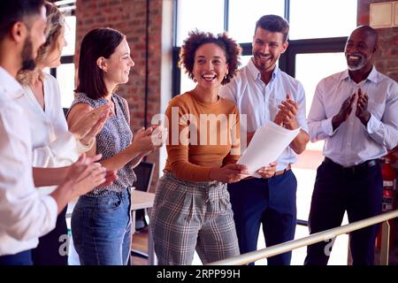 Colleghi che applaudono la riunione del team di una donna d'affari in un ufficio multiculturale molto impegnato Foto Stock