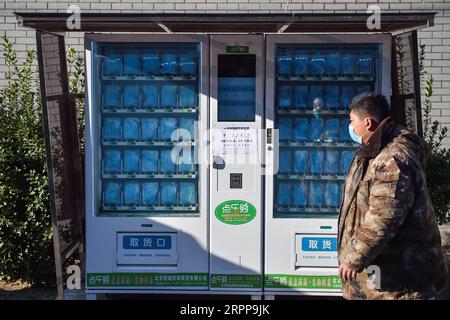 200314 -- PECHINO, 14 marzo 2020 -- Un uomo cammina davanti a un distributore automatico di maschere facciali di nuova costruzione nel distretto di Fengtai di Pechino, capitale della Cina, 13 marzo 2020. XINHUA FOTO DEL GIORNO PengxZiyang PUBLICATIONxNOTxINxCHN Foto Stock