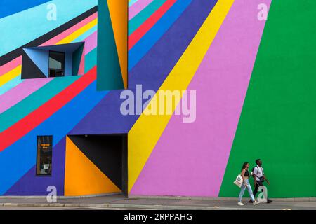 Due persone camminano davanti alla Towner Art Gallery con le colorate opere d'arte Dance Diagonal dell'artista tedesco Lothar Götz a Eastbourne, East Sussex, Regno Unito a settembre Foto Stock