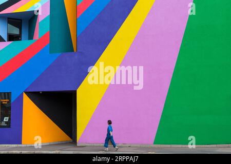 La donna passeggia davanti alla Towner Art Gallery con le colorate opere d'arte Dance Diagonal dell'artista tedesco Lothar Götz a Eastbourne, East Sussex, Regno Unito, a settembre Foto Stock