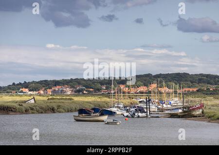 Barche a vela ormeggiate a Morston creek con sfondo al villaggio di Blakeney, North Norfolk Foto Stock