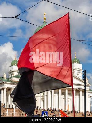 Bandiera rossa e nera volata di fronte alla cattedrale di Helsinki durante la "fine del silenzio!" manifestazione contro il razzismo e il fascismo. Foto Stock