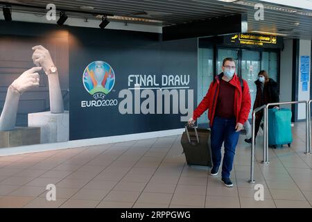 200318 -- BUCAREST, 18 marzo 2020 Xinhua -- le persone che indossano maschere per il viso passano un logo del Campionato europeo di calcio EURO 2020 esposto su un muro all'aeroporto internazionale Henri Coanda di Bucarest, in Romania, 17 marzo 2020. L'organo di governo europeo del calcio UEFA ha deciso di rinviare il Campionato europeo di calcio di quest'estate al 2021 a causa dell'epidemia di coronavirus. Il presidente rumeno Klaus Iohannis ha annunciato che il paese entrerà in uno stato di emergenza a partire dal 16 marzo, nel tentativo di garantire che il governo utilizzi tutte le risorse per combattere l'epidemia di COVID-19. Foto di Cristian Criste Foto Stock