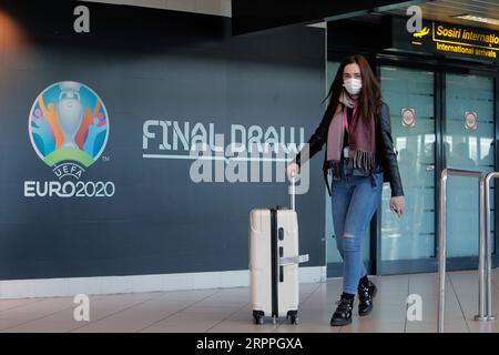 200318 - BUCAREST, 18 marzo 2020 Xinhua - Una donna che indossa una maschera passa davanti a un logo del Campionato europeo di calcio EURO 2020 esposto su un muro all'aeroporto internazionale Henri Coanda di Bucarest, in Romania, 17 marzo 2020. L'organo di governo europeo del calcio UEFA ha deciso di rinviare il Campionato europeo di calcio di quest'estate al 2021 a causa dell'epidemia di coronavirus. Il presidente rumeno Klaus Iohannis ha annunciato che il paese entrerà in uno stato di emergenza a partire dal 16 marzo, nel tentativo di garantire che il governo utilizzi tutte le risorse per combattere l'epidemia di COVID-19. Foto di Cristian Foto Stock