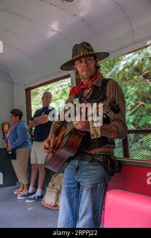 Cantante e intrattenitore che cantano canzoni ai passeggeri per consigli sull'escursione della Great Smoky Mountains Railroad da Bryson City, North Carolina Foto Stock