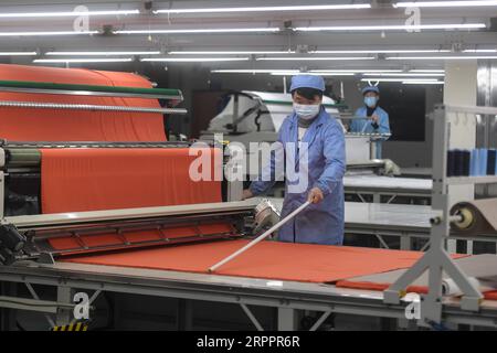 200321 -- PECHINO, 21 marzo 2020 -- i lavoratori sono visti in una fabbrica della Shenzhou International Group Holdings Limited a Ningbo, nella provincia dello Zhejiang, nella Cina orientale, 12 febbraio 2020. Titoli di Xinhua: Fabbriche cinesi ruggenti in piena attività per stabilizzare la catena di fornitura globale HuangxZongzhi PUBLICATIONxNOTxINxCHN Foto Stock