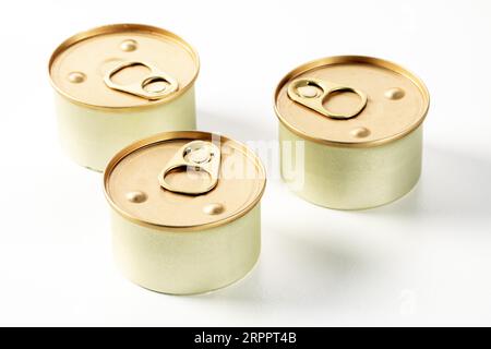 Tre lattine metalliche di cibo per gatti su sfondo bianco. Sulle lattine sono visibili gocce di condensa, che sono state appena estratte dal frigorifero Foto Stock