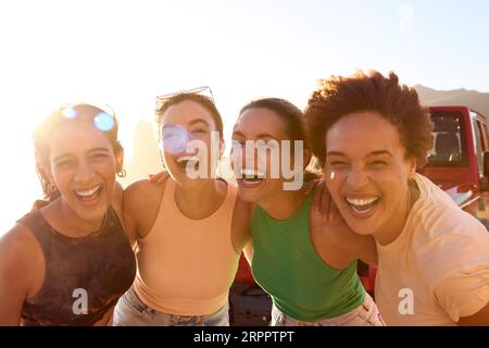 Ritratto delle amiche sorridenti in piedi in auto, divertendosi durante un viaggio in campagna Foto Stock