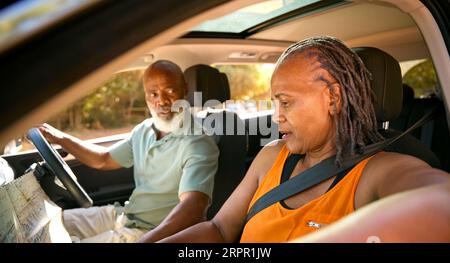 Una coppia di anziani confusi durante la gita di un giorno in auto con la mappa di lettura sembra persa Foto Stock