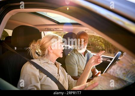 Una coppia di anziani confusi durante la gita di un giorno in auto con la mappa di lettura sembra persa Foto Stock