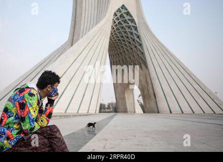 200326 -- TEHERAN, 26 marzo 2020 -- Un uomo che indossa una maschera si siede accanto alla torre Azadi a Teheran, Iran, 25 marzo 2020. Il Ministero iraniano della salute e dell'educazione medica ha riportato 143 nuovi decessi per il virus, portando il bilancio complessivo delle vittime del paese a 2.077 mercoledì. Il totale dei casi confermati è aumentato a 27.017, di cui 9.625 persone si sono riprese. Foto di /Xinhua IRAN-TEHERAN-COVID-19-AZADI TOWER AhmadxHalabisaz PUBLICATIONxNOTxINxCHN Foto Stock