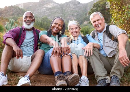 Ritratto di amici anziani attivi seduti che fanno una pausa passeggiando insieme nella campagna Foto Stock